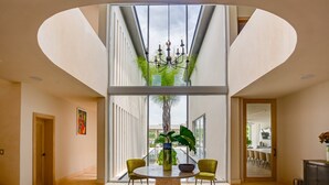 A dining area with a round table, two chairs, a vase with flowers, and a chandelier. - Luxury 8BR Villa Hacienda  Punta Cana (Punta Cana)