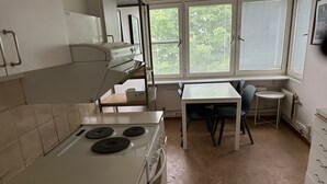A kitchen with a stove, a table, and chairs. - Apartment in Skarholmen, Stockholm 206 (Skärholmen)