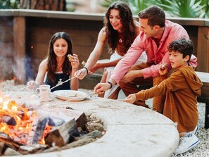 A family gathered around a campfire with a grill, roasting marshmallows. - 2 Bedroom Villa Beach Access at SurfWatch Resort (Hilton Head Island)