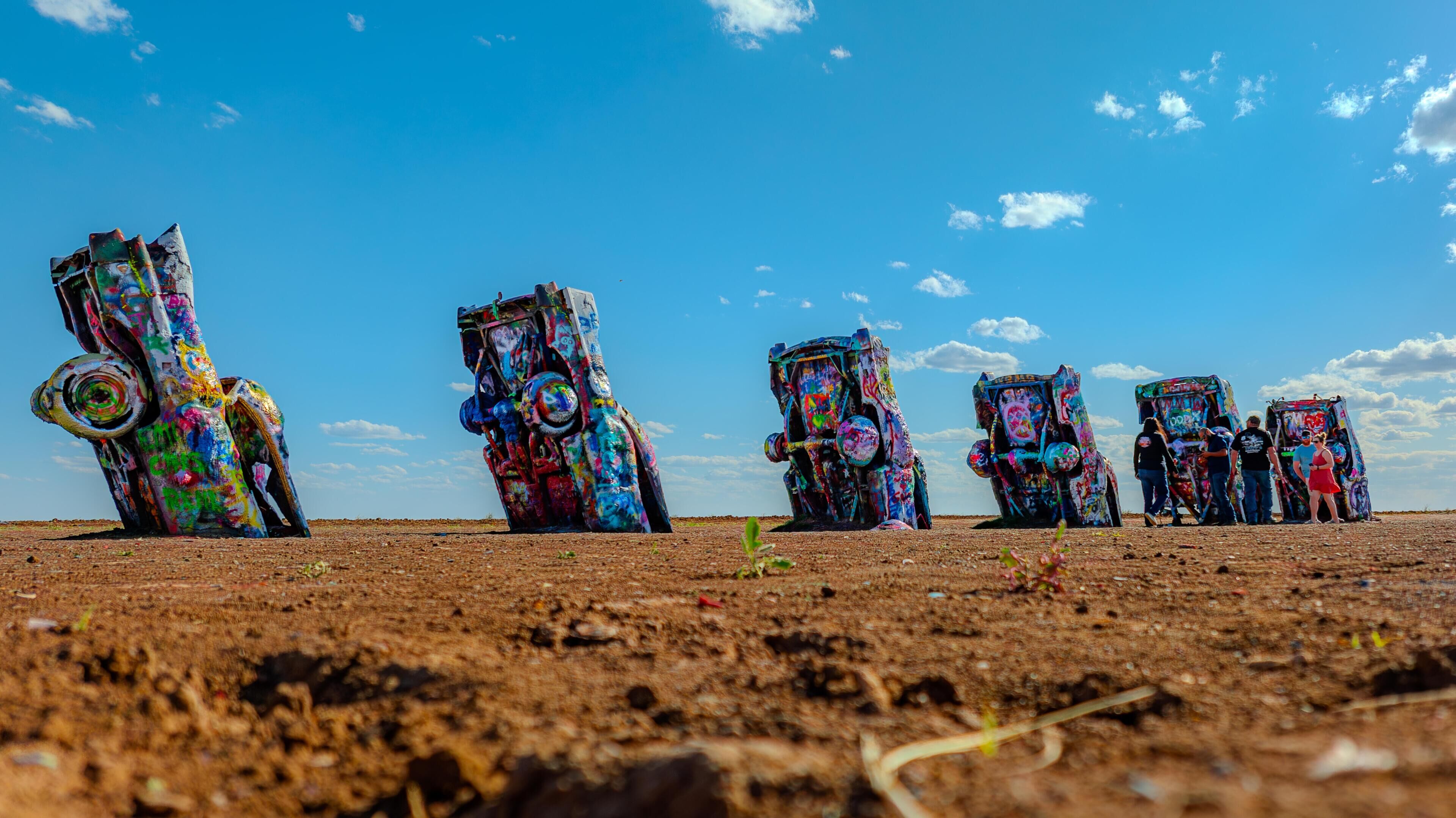 A series of colorful, graffiti-covered sculptures in an open field.