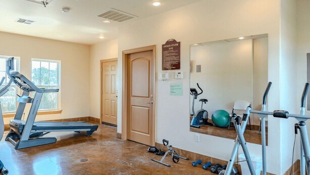Ein Fitnessstudio mit Laufbändern, Crosstrainern und Kurzhanteln.