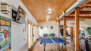 Ein Zimmer mit einem Tischtennisplatte, Holzbalkendecke und verschiedenen Postern an den Wänden.