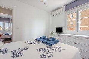A bedroom with a bed, a TV, and a window.