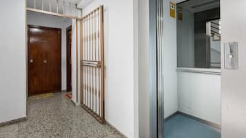 Un pasillo con puerta de madera, una reja de metal y un ascensor.