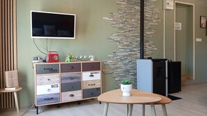 Ein modernes Zimmer mit Fernseher, einer Schubladenschrank, einem kleinen Tisch mit Pflanze und einem Kamin.