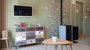 A modern room with a television, a cabinet with drawers, a small table with a plant, and a fireplace. - The Ocean Interlude (Saint-Jean-de-Monts)