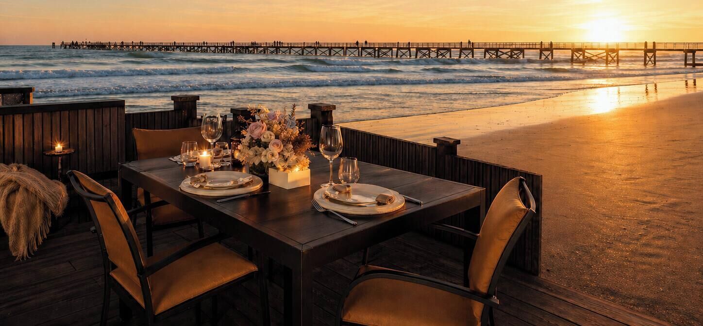 A table set for two with a view of the ocean and a pier in the background.