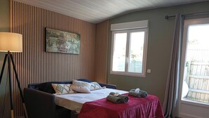 Ein Zimmer mit einem Bett, einer Lampe, einem Fenster und einem Bild an der Wand.