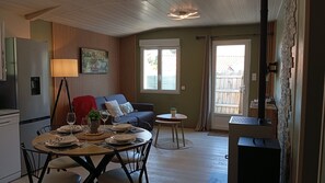 A dining area with a table set for four, a sofa, a small side table, and a refrigerator. - The Ocean Interlude (Saint-Jean-de-Monts)