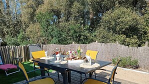 Eine Terrassenausstattung im Freien mit Esstisch, Stühlen und einem Holzzaun.