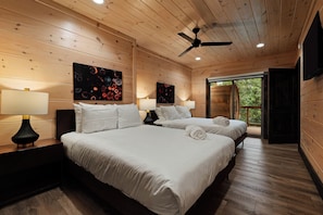 Un dormitorio de cabaña de madera con dos camas, ventiladores de techo y obras de arte en las paredes.
