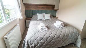 Quarto de hotel com cama, almofadas, janela e radiador.
