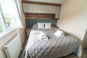 Una habitación de hotel con cama, almohadas, ventana y radiador.