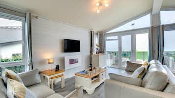 Uma sala de estar moderna com televisão de tela plana, lareira e varanda com vista.