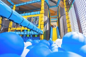 Zona de juegos con estructuras de malla y pelotas azules y blancas.