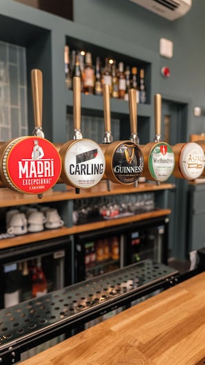 A bar with multiple beer taps, including brands like Madri, Carling, Guinness, and Worthington's.