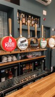 A bar with multiple beer taps, including brands like Madri, Carling, Guinness, and Worthington's.