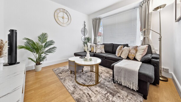 A modern living room with a sofa, coffee table, and a clock on the wall. - Cozy 3bd, Garden, Free Parking, M25,bluewater (Dartford)
