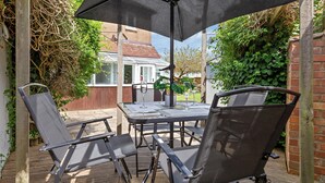 An outdoor patio with a table and chairs, a large umbrella, and a view of a house in the background. - Cozy 3bd, Garden, Free Parking, M25,bluewater (Dartford)