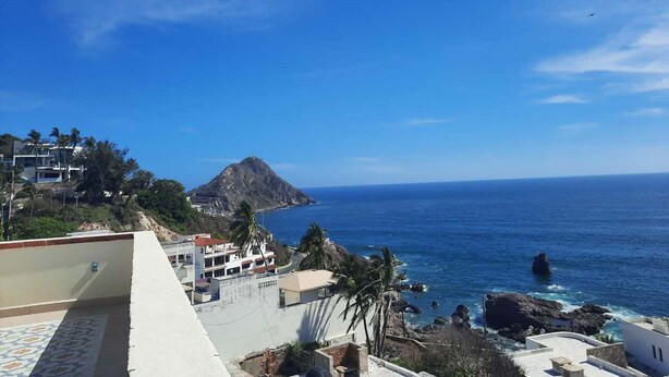 A coastal view with buildings, a mountain, and the ocean. - Serene studio with AC in charming Mazatlán getaway (Mazatlán)