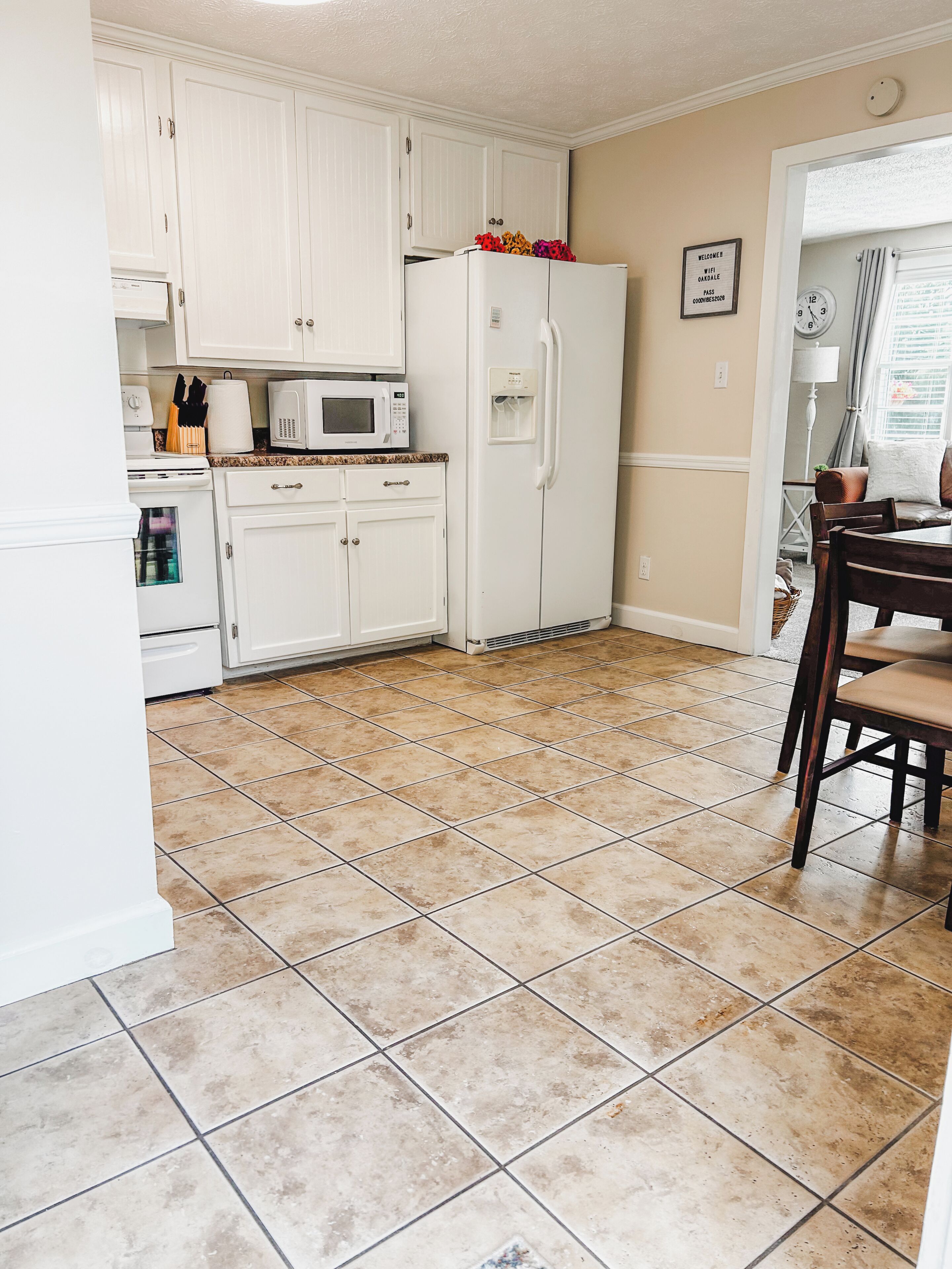 A kitchen with white cabinets, a white refrigerator, a microwave, and a dining area with a table and chairs.