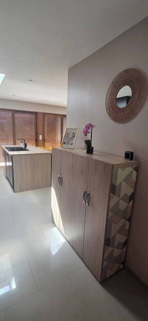 Een moderne keuken met een centraal eiland, houten kastjes en een decoratieve spiegel aan de muur.