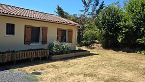 A single-story house with a tiled roof, wooden shutters, and a small garden area with a wooden planter and a bench. - Bed and Breakfast with a Panoramic View 2 (Marcillac-Saint-Quentin)