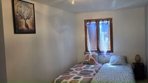 A bedroom with a bed, a window with curtains, a radiator, and a wall-mounted picture. - Bed and Breakfast with a Panoramic View 2 (Marcillac-Saint-Quentin)