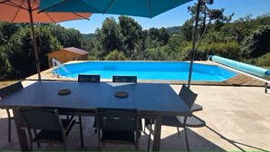 A swimming pool with a slide, surrounded by a patio with a table and chairs, and a small shed in the background. - Bed and Breakfast with a Panoramic View 2 (Marcillac-Saint-Quentin)