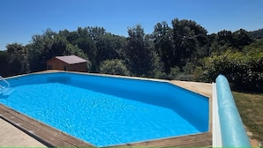Ein rechteckiger Pool mit Holzterrasse und einer Leiter an einer Seite.