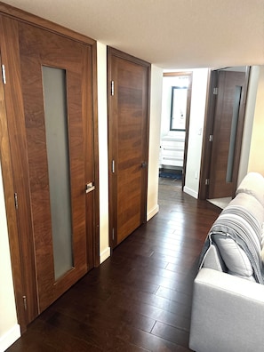 Un couloir avec des portes en bois, un canapé et un sol carrelé.