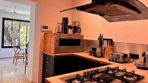 A modern kitchen with a gas stove, a microwave, a coffee maker, and a toaster. - Villa Apolline · 1892 Estate · 5 BR, Heated Pool, Riviera Views (Grasse)