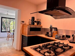 A modern kitchen with a gas stove, a microwave, a coffee maker, and a toaster.
