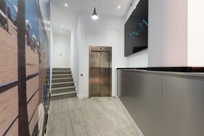 Eine moderne Lobby mit Holzboden, einer Treppe und einem wandmontierten Aufzug.