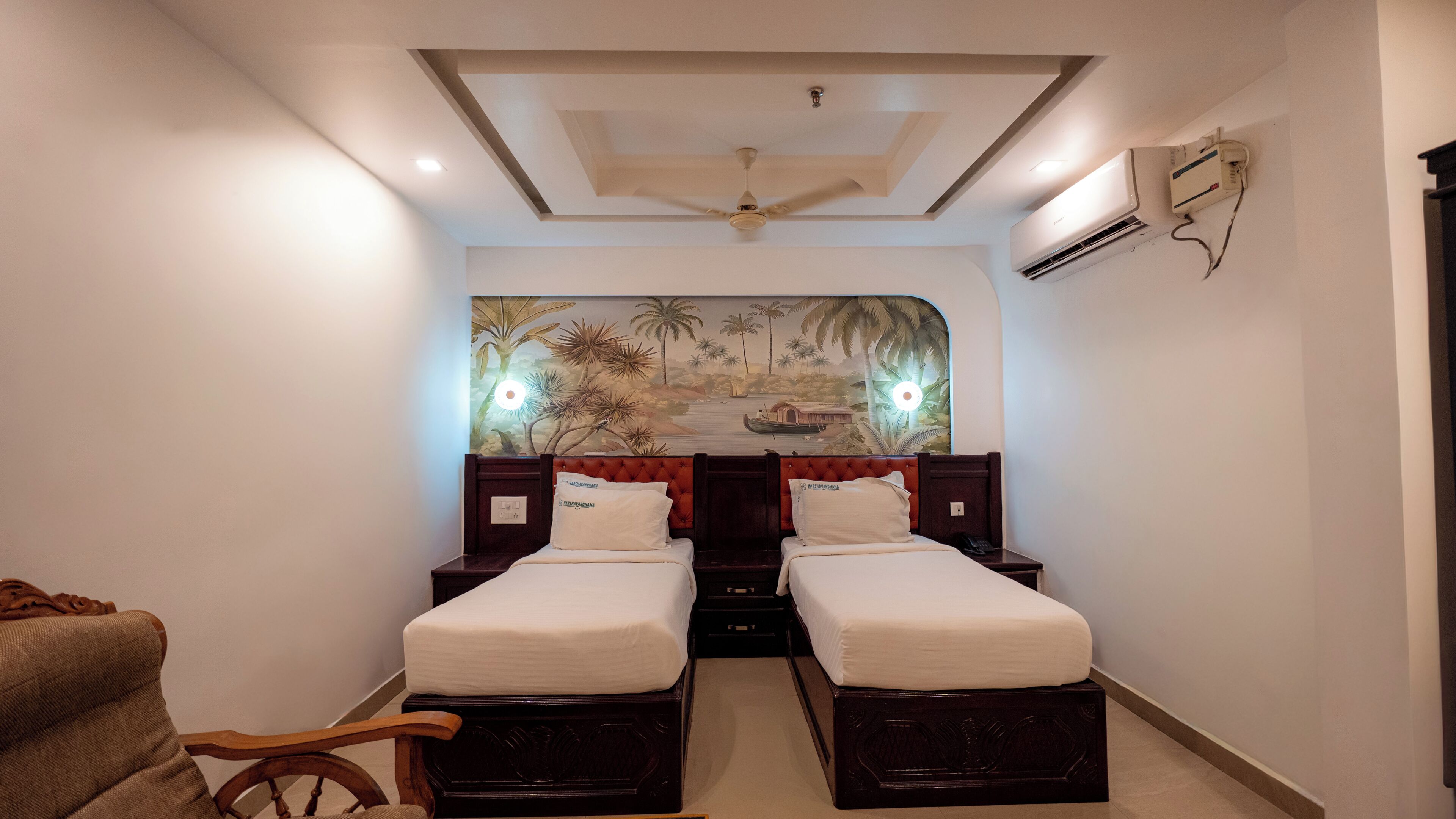 Une chambre d’hôtel avec deux lits simples, un ventilateur de plafond, un appareil de climatisation et une fresque murale.