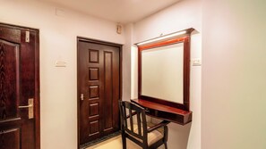 A room with a wooden door, a mirror, and a chair.