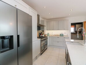 A modern kitchen with stainless steel appliances, white cabinetry, and a tiled floor. - Balcarry Barn (Newton Stewart)
