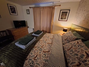 A bedroom with a bed, a dresser, a television, and a lamp. - Dolcoed (Llandeilo)