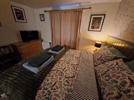 Un dormitorio con cama, cómoda, televisor y lámpara.