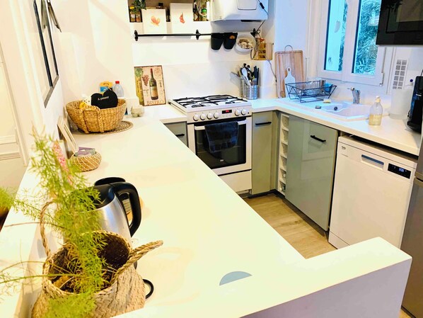 Una cocina moderna con estufa a gas, horno, lavavajillas y muebles blancos.