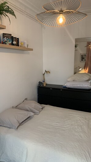 Ein Schlafzimmer mit einem Bett, einem Nachttisch, einer Lampe, einem Bücherregal und einer Pendelleuchte.