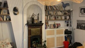 Een gezellige woonkamer met een open haard, een boekenkast, een ronde tafel en een hanglamp.