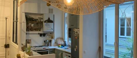 A modern kitchen with white cabinetry, a central island, and a hanging light fixture.