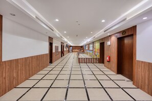 Ein Hotelgang mit Holzvertäfelung, Fliesenboden und eingelassener Beleuchtung.