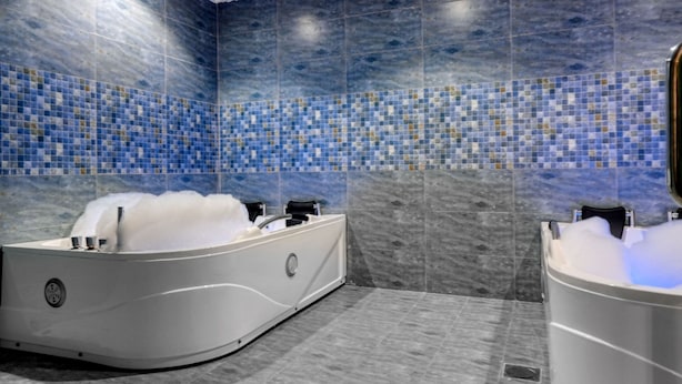 A modern bathroom with a jacuzzi, a separate bathtub, and a large mirror. - Aluya Al Marwa Hotel (Jeddah)