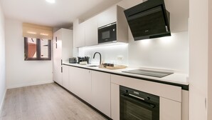 A modern kitchen with white cabinetry, a Bosch microwave, a built-in oven, and a black range hood.