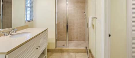 Une salle de bain avec un meuble-lavabo à deux vasques, une douche à parois de verre et un miroir.