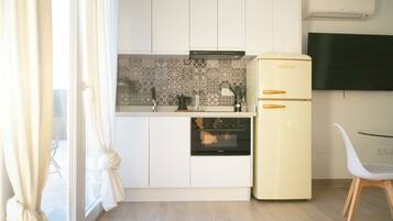 Una cocina compacta con armarios blancos, horno integrado y refrigerador amarillo.