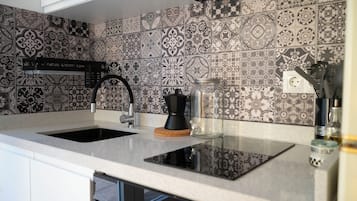 Een keuken met een zwart-wit tegelpaneel, een zwarte kraan en een koffiezetapparaat op het aanrecht.