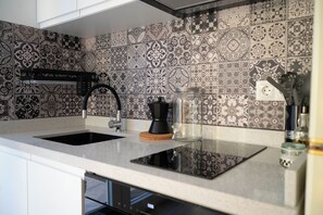 A kitchen with a black and white patterned backsplash, a black faucet, and a coffee maker on the counter.